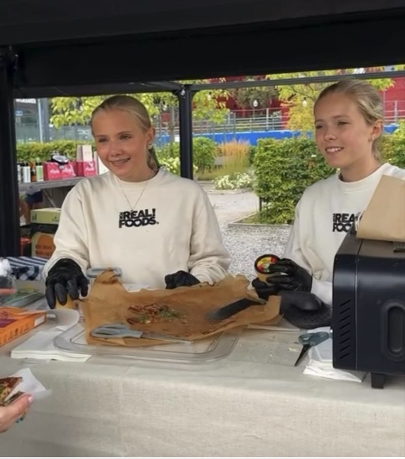 Två unga demonstratörer bakom ett demobord vid ett event
